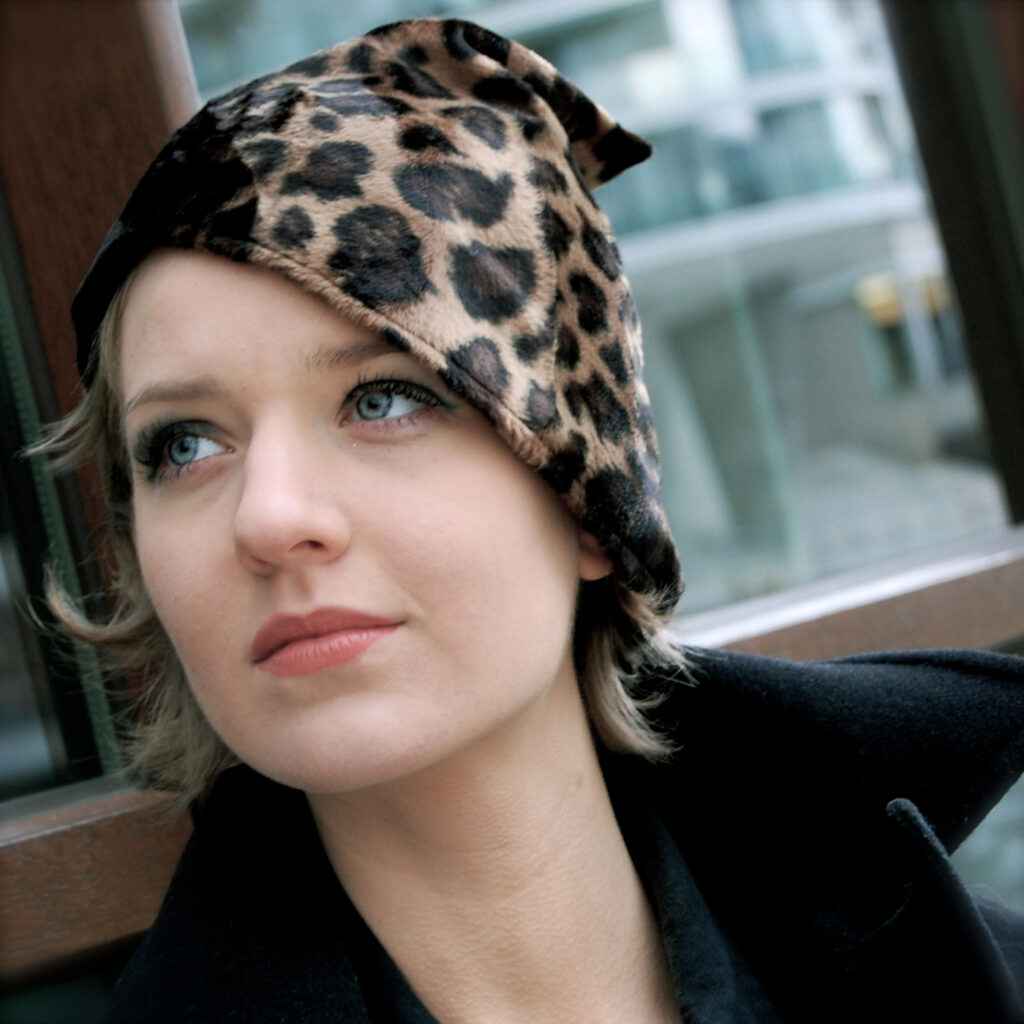 Eine Frau trägt eine Kopfbedeckung mit Leo-Optik.